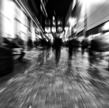 abstract zoom blur of a modern city street at night with people walking 