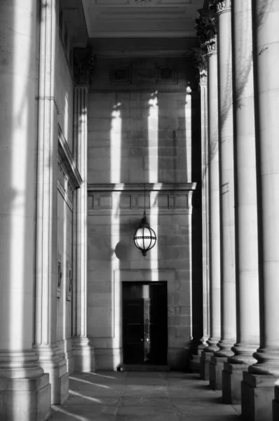 monochrome tall classical columns stone walls and door in sunlight and shadow in the portico of leeds town hall in west yorkshire