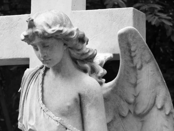 Ángel de mármol blanco en una lápida con una cruz detrás en un viejo — Foto de Stock