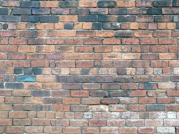 Vieux mur de briques rouges rugueuses avec briques noircies et réparation — Photo