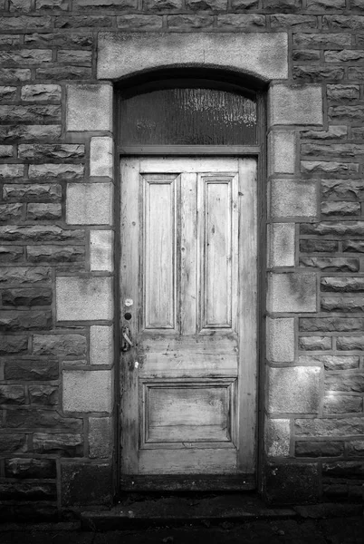 Старі зів'ялі дерев'яні двері будинку з кам'яною стіною — стокове фото