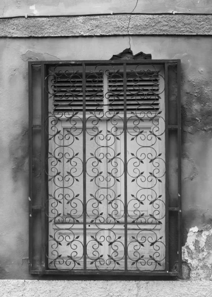 Fenêtre à volets en bois blanc derrière des barreaux de fer forgé sur un fondu — Photo