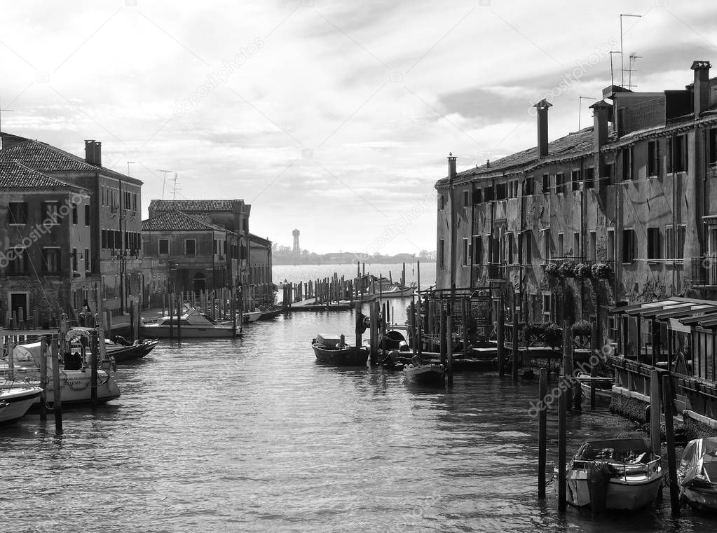 Monochrome image of the guidecca area of venice with boats moored next to historic old buildings