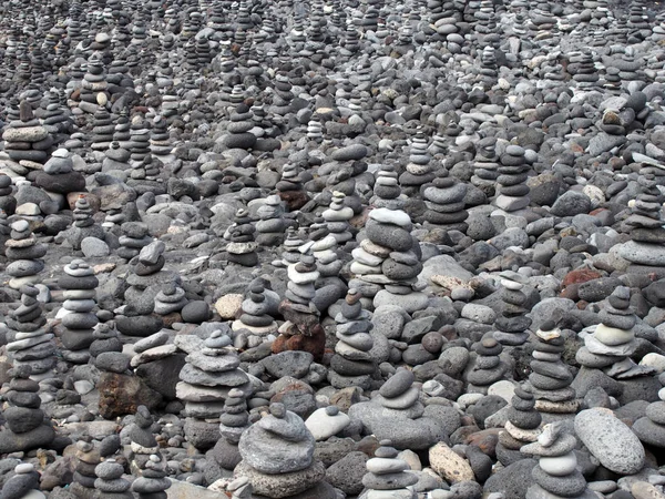 Guijarros grises y piedras en una playa dispuestas en una gran colección de pilas y torres que llenan el marco — Foto de Stock