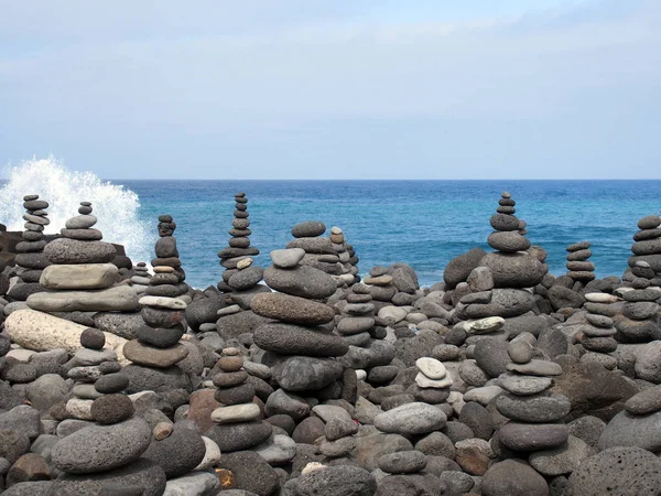 岩石艺术堆和灰色石头和鹅卵石塔在海滩上与蓝天和蓝天与破浪 — 图库照片
