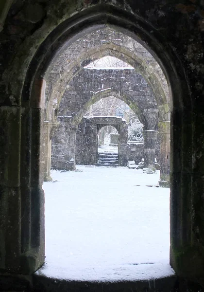 Snow falling through a ruined old church door in heptonstall in — Stock Photo, Image