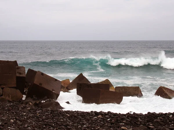 海浪冲破混凝土立方海防线和鹅卵石海滩 — 图库照片