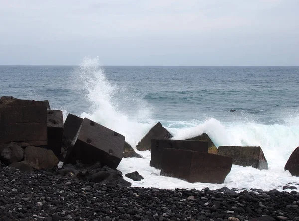 Olas rompiendo sobre las defensas marinas cúbicas de hormigón en tenerife con —  Fotos de Stock