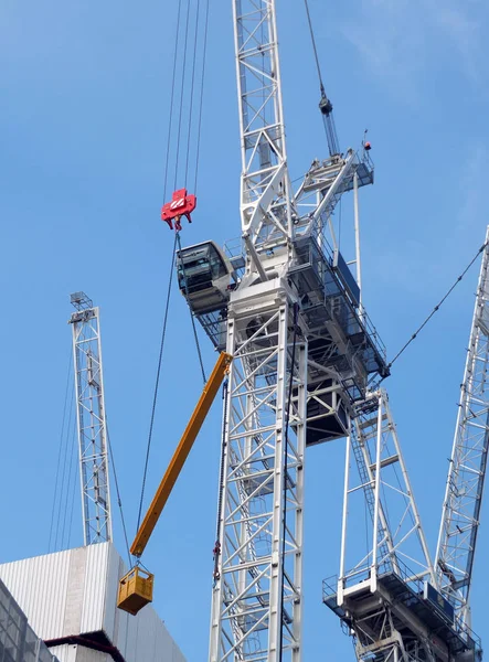 Grúas de construcción de gran altura que trabajan en un gran sitio de desarrollo con estructura de hormigón grande —  Fotos de Stock