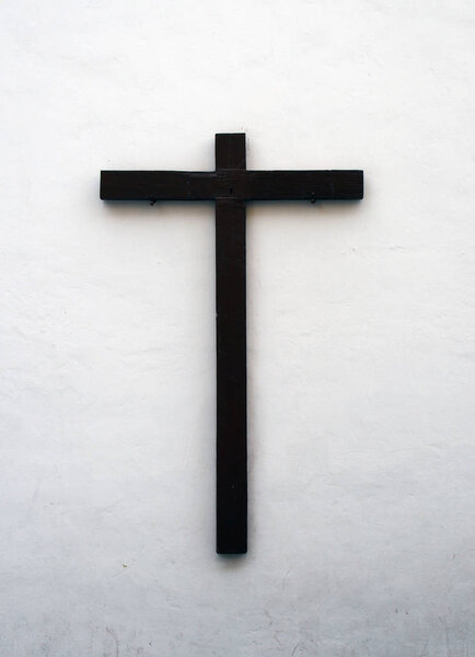 wooden cross on an outside white wall in spain