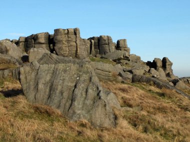 Bridestones 'da engebeli yulaf taşı uzanır. Batı Yorkshire' da büyük bir kaya oluşumu. Mavi gökyüzü ve çevresindeki kırsal bölgeler ile yarının yakınında.