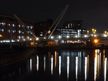 Leeds 'in Clarence rıhtım bölgesine kanal girişinin bir şehir manzarası ile bir yaya köprüsü ve bulutlar ile bir gece gökyüzüne karşı ışıklar ve binaların yansımaları ile su geçişi