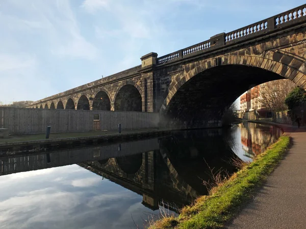 Ancien viaduc ferroviaire abandonné traversant le canal dans le centre-ville de Leeds près de la route whitehall avec arc réfléchi dans l'eau — Photo