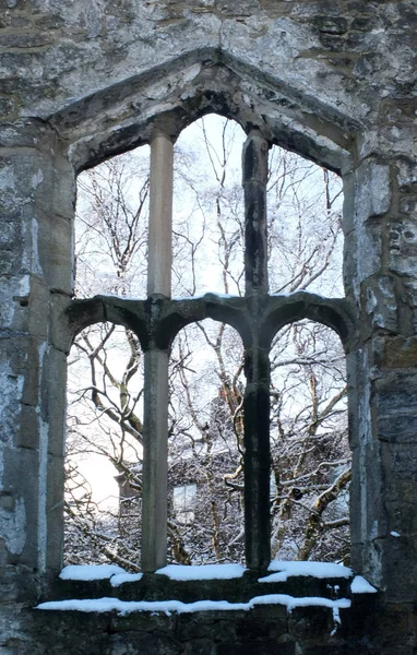 Vista a través de una ventana de una iglesia medieval en ruinas en heptonstall yorkshire con árboles cubiertos de nieve detrás del marco de piedra —  Fotos de Stock