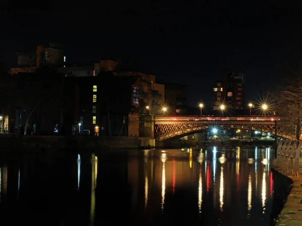 Crown Point Bridge oversteken van de rivier de Aire in Leeds 's nachts met verlichting en de omliggende gebouwen weerspiegeld in het water — Stockfoto