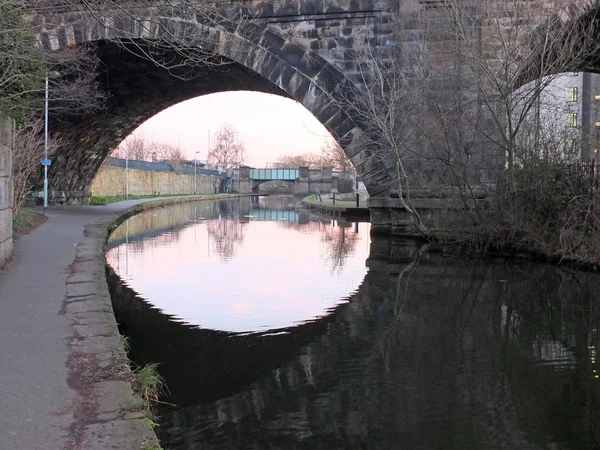 Velho viaduto ferroviário abandonado que atravessa o canal no centro da cidade de Leeds perto da estrada whitehall com arcos refletidos na água — Fotografia de Stock