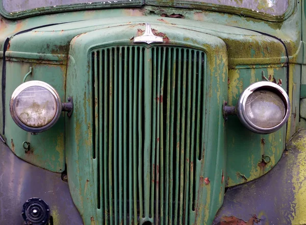 Close up of the front of an old abandoned rusting green truck covered in moss — Stock Photo, Image