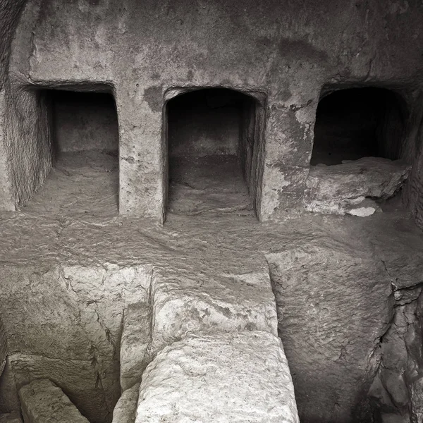 Imagem monocromática de um túmulo subterrâneo escuro com ponte de pedra conectando câmaras funerárias em paphos cyprus — Fotografia de Stock