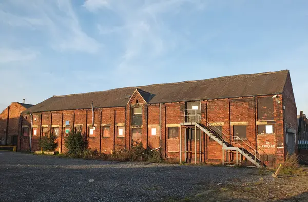 Ein altes verlassenes Ziegelfabrikgebäude mit vergitterten Fenstern und Stahltreppe, überwuchert mit Unkraut in Leeds england — Stockfoto