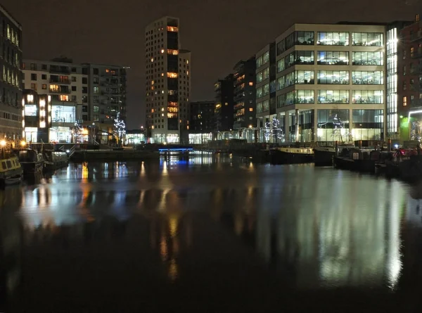 Clarence doca em leeds à noite com edifícios brilhantemente iluminados refletidos na água e barcos ancorados ao longo dos lados — Fotografia de Stock