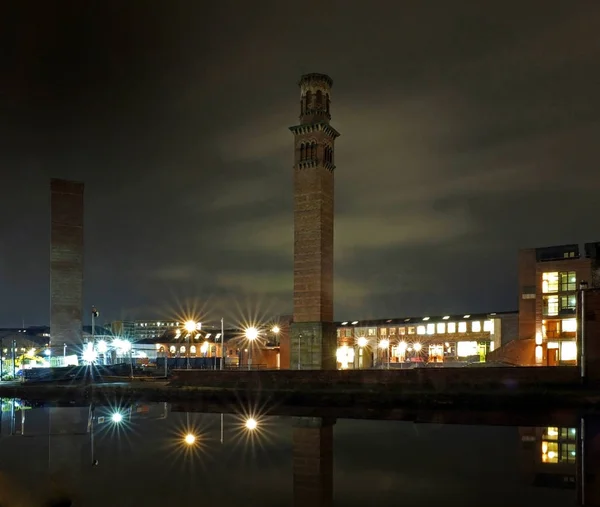 Vista sul paesaggio urbano di holbeck a sud leeds che mostra le opere storiche torre di notte con edificio per uffici e luci riflesse nel canale — Foto Stock