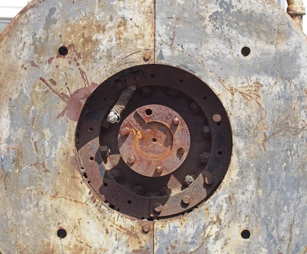 Fermer les détails du cadre complet des vieilles machines à rouiller avec trou circulaire dans les plaques d'acier avec boulons et arbre d'entraînement rond au centre dans la lumière du soleil et l'ombre — Photo