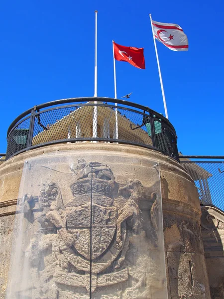 Turco no norte bandeiras ciprus que voam acima e edifício velho com os restos de um brasão de armas britânico em nicosia — Fotografia de Stock