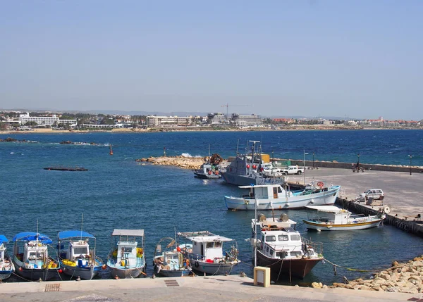 Bateaux de pêche et yachts amarrés dans le port de Paphos avec vue sur les bâtiments en bord de mer et la ville au loin — Photo