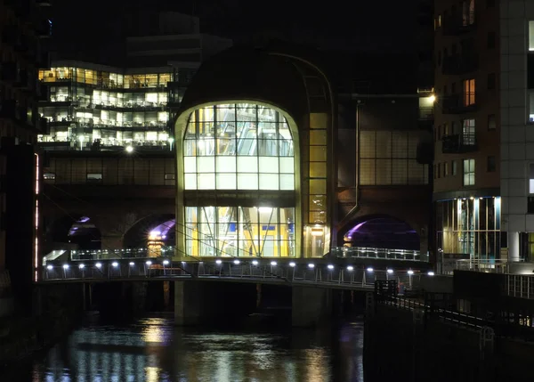 A cityscape night view of leeds showing the river aire running under the dark arches and the southern entrance to the station surrounded by illuminated office developments — ストック写真