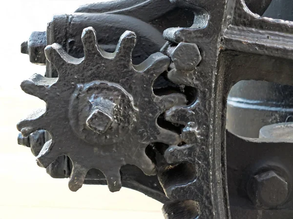 Un gros plan de vieilles grandes roues dentées peintes en noir usé avec des dents d'engrenage sur des machines industrielles obsolètes ; — Photo