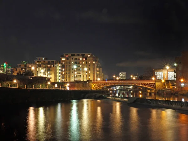The river aire in leeds at night showing buildings on both sides of crown point bridge and the weir with bright lights reflected in the water — Stock Photo, Image