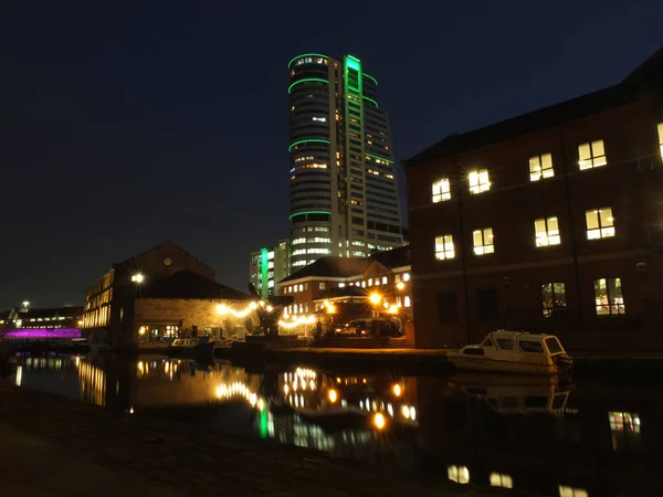 Sanguijuelas muelle del canal por la noche con edificios iluminados y cerradura reflejada en el agua y brillando contra un cielo oscuro — Foto de Stock