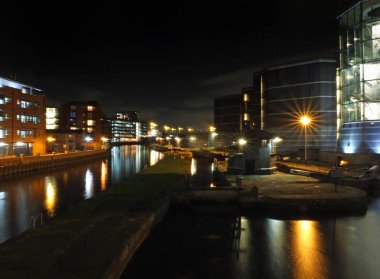 şehir binaları ile gece Leeds Clarence Dock kanal tarafında kilit giriş ve iskeleler su ve parlayan sokak ışıkları yansıyan