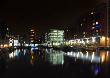 gece Leeds 'de Clarence Rıhtımı parlak aydınlatılmış binalar ile su ve gemiler kenarları boyunca demirli yansıyan