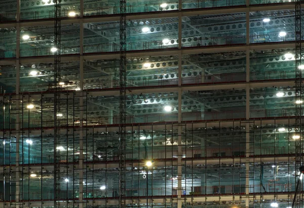 Vollbild-Ansicht einer Großbaustelle in der Nacht beleuchtet durch helle Arbeitsscheinwerfer mit Trägern und Bauzügen — Stockfoto