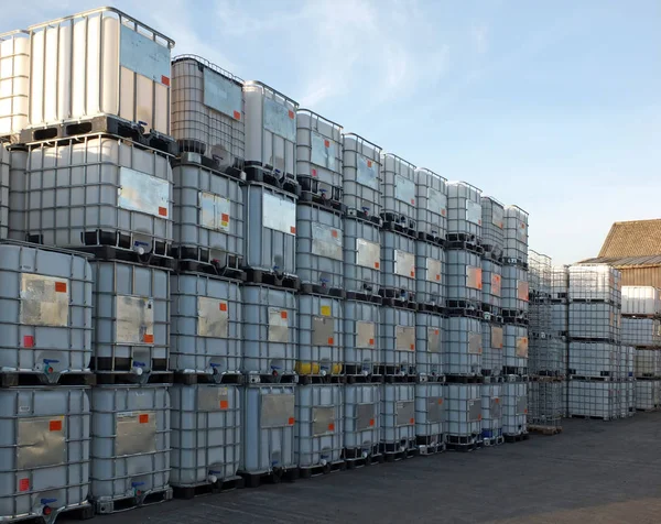 Used metal framed intermediate bulk containers stacked on pallets waiting to be cleaned or recycled in an industrial yard — Stock Photo, Image