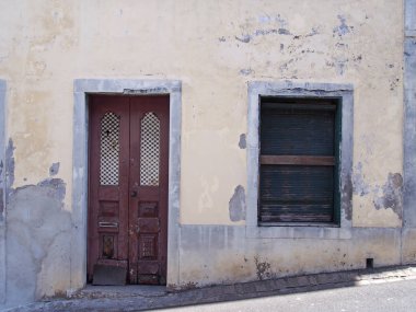 çöken sarı boyalı duvarlar ile boş terk edilmiş ev aşağı bir çalışma kapalı kepenkler ve funchal portekiz eğimli bir sokakta kırık bir ahşap kapı