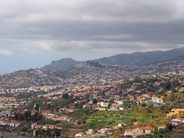 uzakta dağlar ve bulutlu gökyüzü ile çiftlikleri ve evleri ile Madeira funchal eteklerinde hava cityscape görünümü