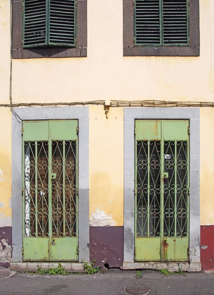 황색과 붉은 색의 벽과 펑샬 마데이라셔셔가 있는 버려진 상점 앞에서 화려한 격자 가있는 녹슨 녹색 금속 문 — 스톡 사진
