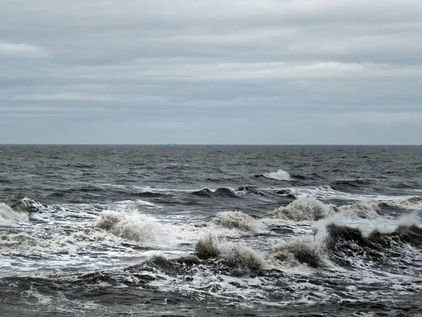 stormy sea with dark waves and surf with a grey winter sky