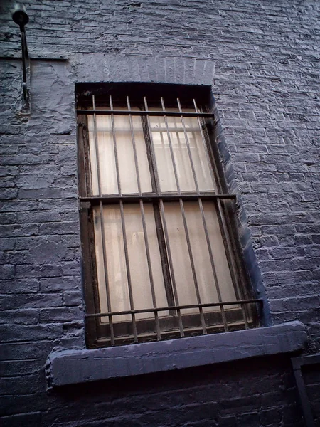 old metal window with metal bars in black painted wall