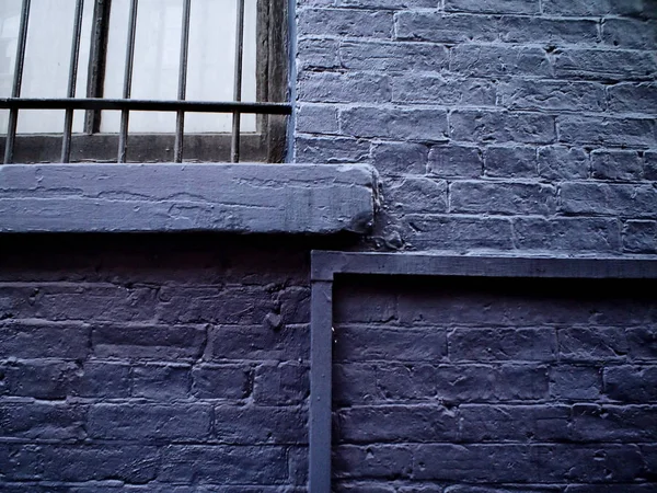 Detail image of an old metal window with metal bars in a black painted wall — Stock Photo, Image