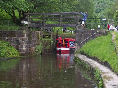 a group of people taking a narrowboat though a lock gate on the rochdale canal in hebden bridge west yorkshire