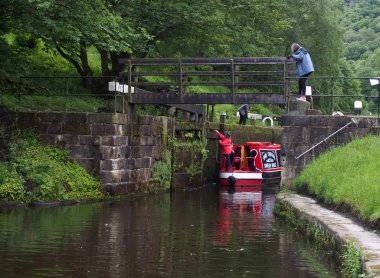 a group of people taking a narrowboat though a lock gate on the rochdale canal in hebden bridge west yorkshire