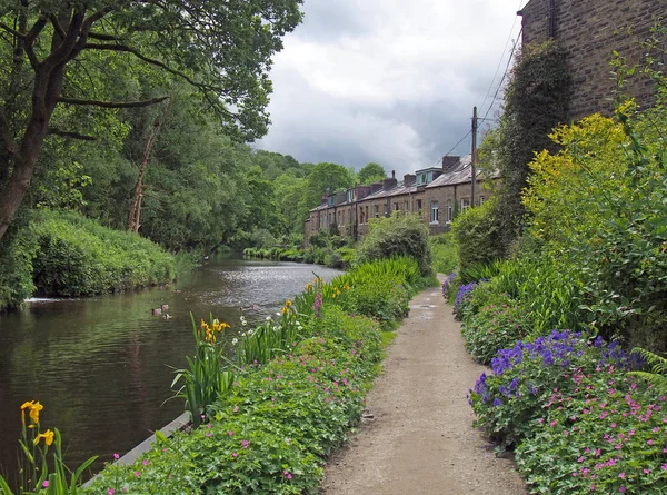 Un chemin de canal entouré de fleurs d'été avec une rangée de vieilles maisons en pierre à l'est dans hebden pont ouest yorkshire — Photo