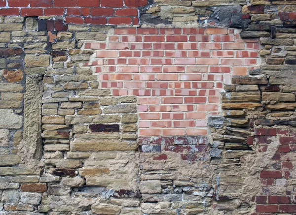 Large old wall made of mixed bricks and stone with many jumbled patched and uneven repairs — Stock Photo, Image