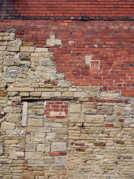 A full frame image of a large old wall made of mixed bricks and stone with many patched and uneven repairs — Stock Photo, Image