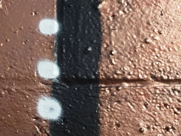 Miedziana farba natryskowa na ścianie z czarnym paskiem i białymi kropkami — Zdjęcie stockowe