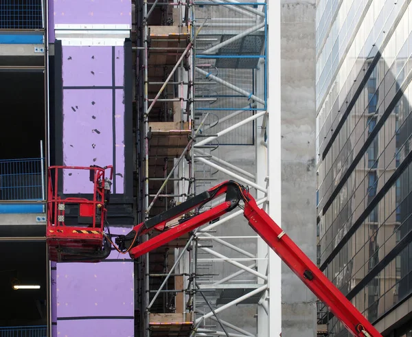 Eine leere rote Arbeitsbühne auf einer städtischen Großbaustelle mit Baugerüsten — Stockfoto