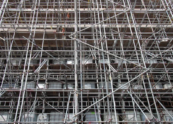 Scaffolding on a construction siteshowing ibc water filled intermediate bulk containers used as ballast on each level — Stock Photo, Image